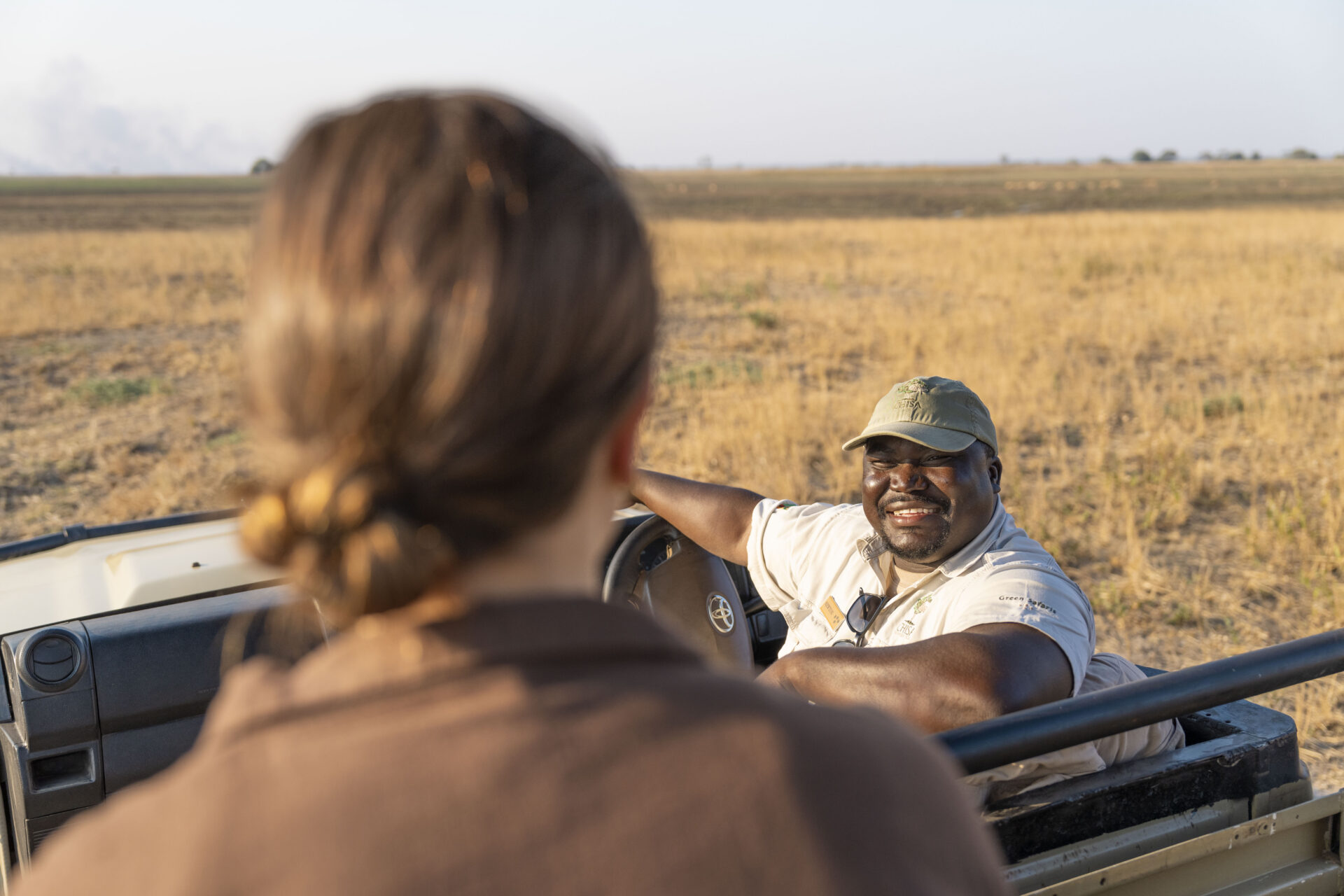 Guest chatting with her guide from an open game drive vehicle at Chisa Busanga Camp in Kafue National Park