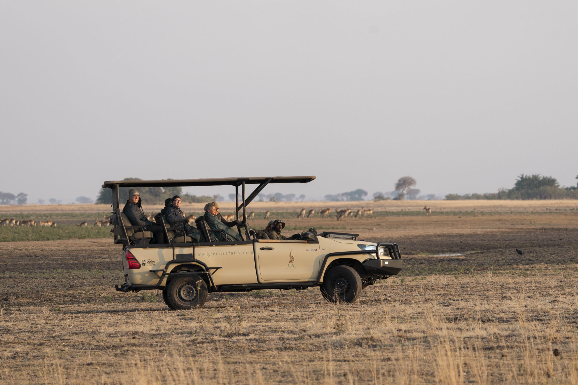 Green Safaris game drive vehicle crossing the open Busanga Plains in Kafue National Park, Zambia